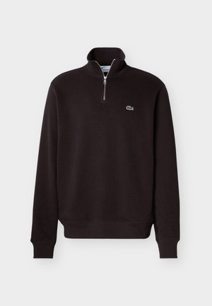 Μαύρο φούτερ με μακριά μανίκια, γιακά με φερμουάρ μέχρι το μέσον και μικρό πράσινο λογότυπο κροκοδείλου στο αριστερό στήθος.