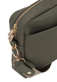 Olivengrøn stoftaske med en tekstureret overflade, prydet med en guldfarvet lynlås, metallisk hardware og en aftagelig rem med trykknap.