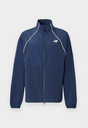 Navy blue windbreaker jacket, featuring a high collar, full-length zipper, elastic cuffs, and reflective white accents along seams.
