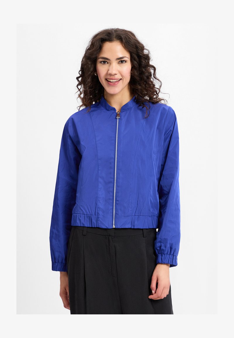 Gekürzte blaue Bomberjacke aus leichtem Material, mit durchgehendem Reißverschluss und elastischen Bündchen, die eine glatte Textur und ein minimalistisches Design aufweist.