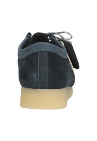 Laivastonsininen mokkanahkakenkä, jossa on teksturoitu pinta, pehmustettu kaulus ja vaaleasävyinen pohja. Ominaisuuksiin kuuluu kontrastivärinen ommel ja harmaat nauhat.