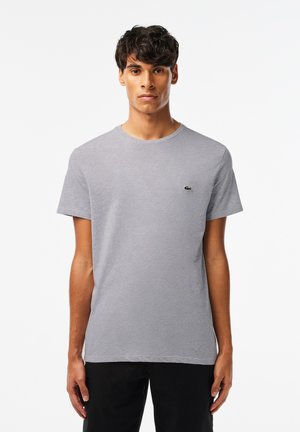 Grijze katoenen t-shirt met een ronde hals, korte mouwen en een klein groen krokodil-logo op de borst. Zachte textuur, ontspannen pasvorm.