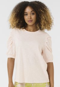 T-shirt in cotone rosa chiaro con maniche corte a sbuffo e scollatura a girocollo. Texture morbida e vestibilità rilassata. Design semplice e minimalista.