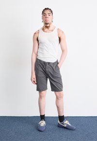 Débardeur gris clair et shorts charbon avec taille élastique. Assorti avec des chaussettes foncées et des baskets bleues avec des accents crème.