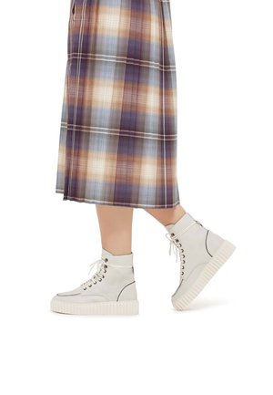 Baskets montantes en cuir blanc avec une semelle en caoutchouc épaisse, un design à lacets et des détails de couture foncés contrastés.