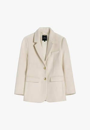 Kremowa dopasowana marynarka z wyciętymi klapami, dwoma złotymi guzikami, kieszeniami z klapkami oraz łańcuszkiem wewnątrz przy kołnierzu.