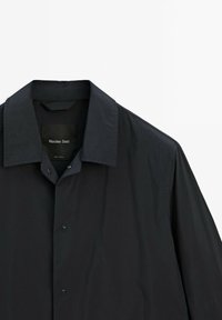 Sort skjorte med knaplukning og bred krave, udstyret med en glat stofoverflade og et mærke, der angiver "Massimo Dutti."