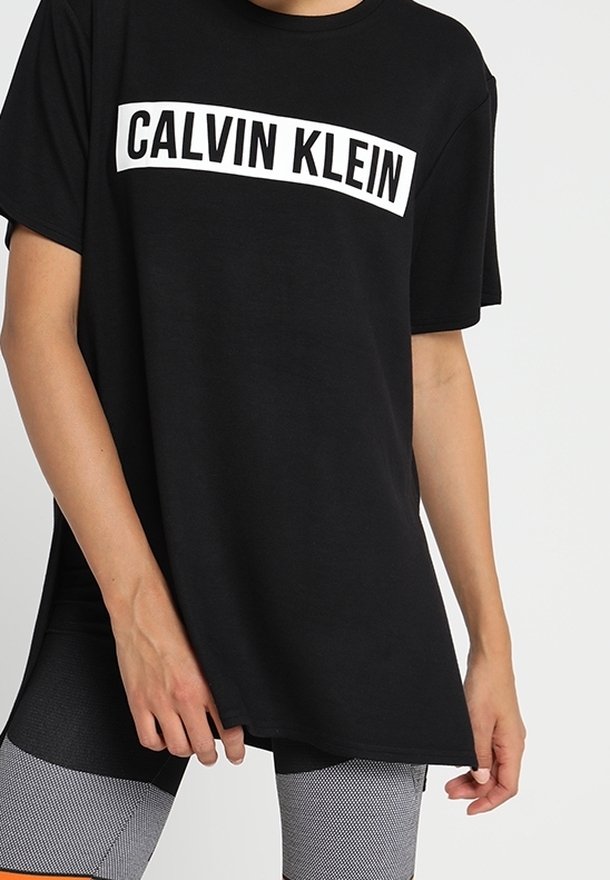 Sort bomulds T-shirt med en hvid "CALVIN KLEIN" logo på brystet, afslappet pasform, kortærmet og rund halsudskæring.