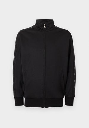 Čierna mikina na zips s vysokým stojacím golierom, bočnými vreckami, rebrovanými manžetami a bielymi prerušovanými pruhmi pozdĺž rukávov.