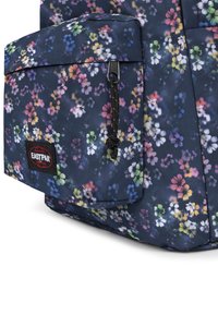 Sac à dos bleu marine à motifs floraux avec une surface texturée, équipé d'une poche avant, de pièces métalliques noires et d'un logo Eastpak.