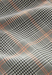 Tissu à motif pied-de-poule en noir et blanc, avec des lignes orange. Le tissu a une texture lisse et un design géométrique complexe.
