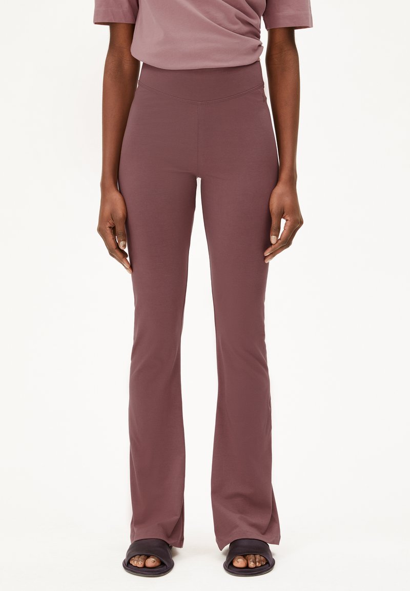 Mauve flared leggings with a high waistband, made of smooth, stretchy fabric, paired with dark slide sandals.