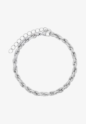 Sidabrinė grandinėlė su susipynusiomis jungtimis, turinti krabų tipo užsegimą ir reguliuojamą grandinėlės ilgį, leidžiantį keisti dydį. Lygus, blizgantis paviršius.