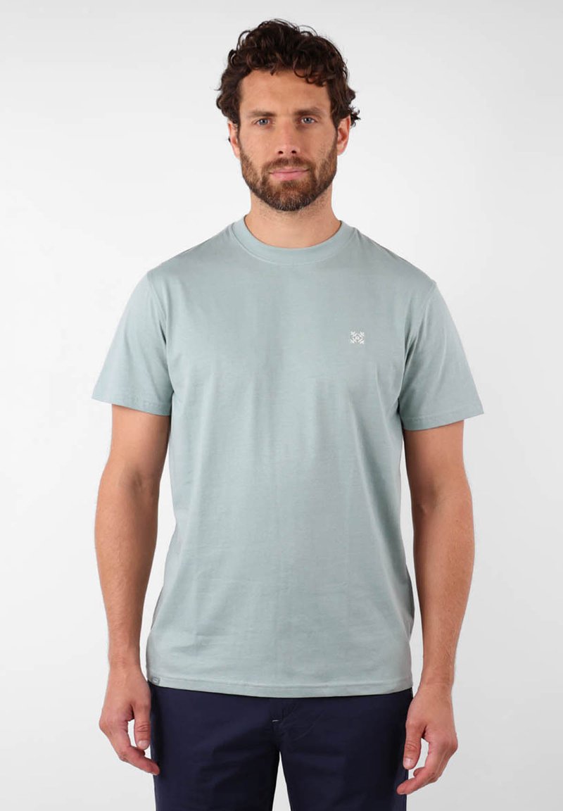 T-shirt en coton vert clair avec un col rond, des manches courtes et un subtil design de logo sur la poitrine gauche. Texture lisse.
