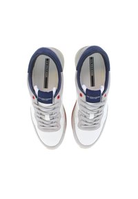 Zapatillas blancas con acentos de ante gris, cuello azul marino y detalles rojos. Presentan cordones planos y una lengüeta acolchada con marca en el interior.