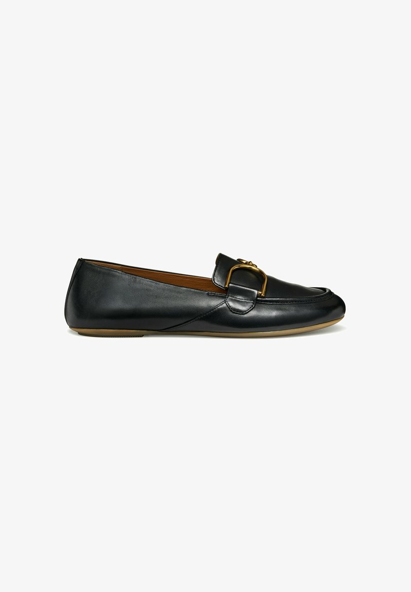 Mocassins de couro preto com bico arredondado, apresentando um detalhe em fivela dourada no peito do pé e uma sola de borracha plana. Textura suave.
