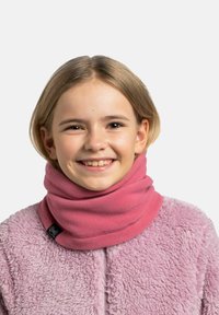 Niño sonriente con cabello rubio corto, que lleva una chaqueta de forro polar rosa y un cubrecuello rosa, frente a un fondo liso.