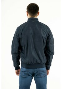 Giacca bomber blu con un motivo sottile, polsi e vita a costine, e colletto rialzato. Presenta un dettaglio del logo sul retro e una texture liscia.
