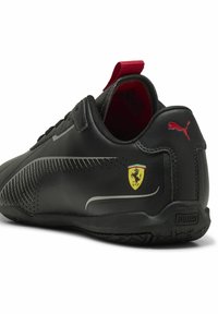 Čierna kožená obuv s červenými akcentmi, s strieborným dizajnovým detailom a logom. Obsahuje erb Ferrari na boku a textúrovanú podrážku.