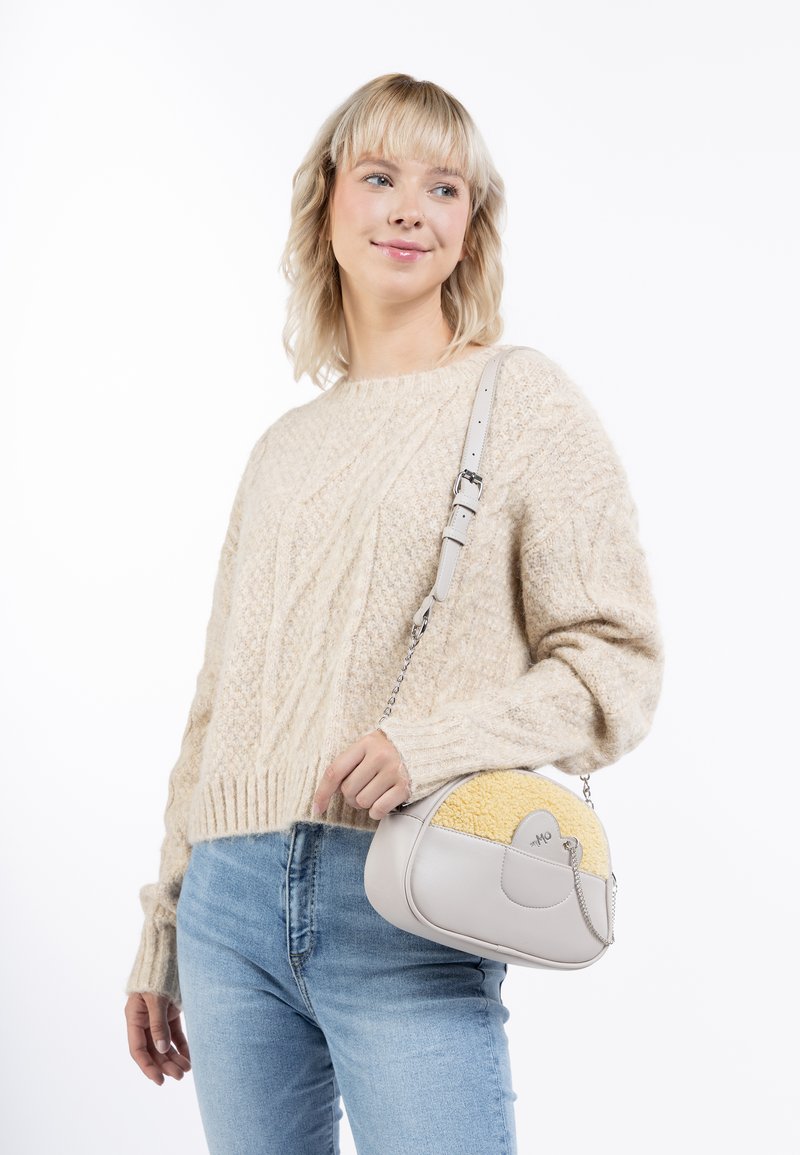 Crossbody taske med en lys grå læderkrop, gul tekstureret accent, rund form, kædesnor og et mærke-detalje på forsiden.