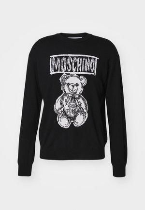 Suéter negro con un gráfico blanco de un oso, con el texto "Moschino" arriba. Textura de punto y mangas largas con puños acanalados.