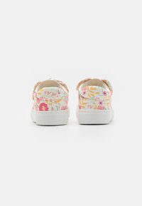 Bloemen canvas sneakers met een witte zool, voorzien van een kleurrijk patroon van roze, gele en groene bladeren en bloemen op een lichte achtergrond.