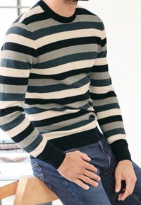 Pull en maille rayé en navy, gris et crème ; col rond, poignets et ceinture côtelés ; style ajusté avec des rayures horizontales.