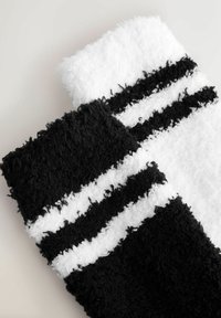Schwarz-weiße gestreifte Socken aus weichem, flauschigem Material, mit zwei dicken horizontalen Streifen und einer strukturierten Oberfläche.