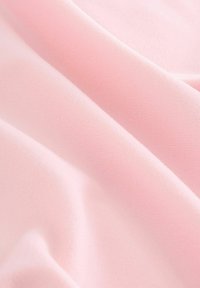 Tessuto di un morbido rosa chiaro con una texture liscia, caratterizzato da una sottile rigatura e pieghe delicate, che creano un aspetto drappeggiato.