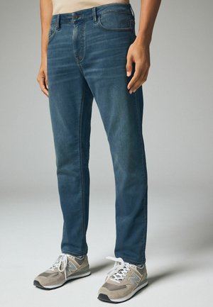 Mørkeblå denim jeans i slim fit, medium høj talje, kontrasterende syninger og et klassisk femlomme-design. Blegningsdetaljer på lårene.