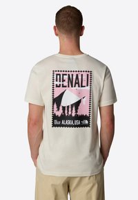 Tričko s krátkým rukávem, krémové barvy, s grafickým potiskem Denali v růžových a černých odstínech, stromy a nápis "DENALI, ALASKA, USA" na zadní straně.
