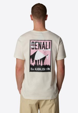 Kortærmet, cremet t-shirt med et grafisk print af Denali i pink og sort, med træer og teksten "DENALI, ALASKA, USA" på bagsiden.
