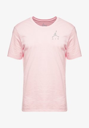 Vaaleanpunainen lyhythihainen T-paita, joka on valmistettu puuvillasta. Rintamalla on harmaa Jumpman-logo ja "AIR"-teksti. Paita on pyöreäkauluksinen ja siinä on teksturoitu kangas.