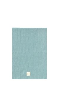 Quadrato di tessuto a maglia blu chiaro con una piccola etichetta bianco sporco che presenta simboli minimalisti vicino a un bordo.