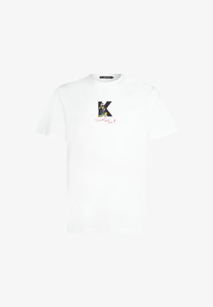 Hvid bomulds t-shirt med et sort bogstav "K" og en tegneseriefigur samt rød håndskrevet tekst nedenfor. Rund halsudskæring og korte ærmer.