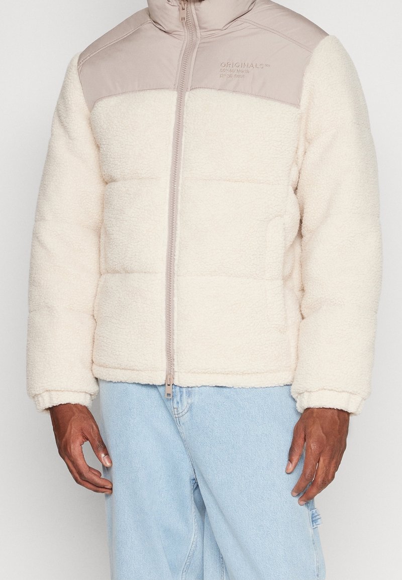 Krämfärgad fleecejacka med en slät beige axelpanel, dragkedja, och ribbade ärmslut, med en pösig design och sidofickor.