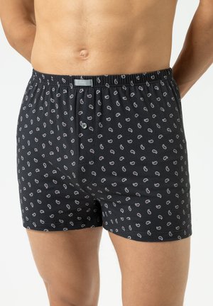 Black boxer shorts featuring a small, repeated paisley pattern in white and red. Made from soft fabric with an elastic waistband and button closure.