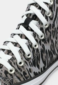 Adidași înalți cu un design în imprimeu leopard gri și negru, șireturi albe, ochiuri din metal și o talpă din cauciuc neagră.