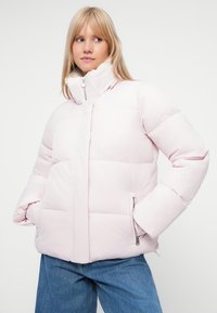 Padded roza jakna z visokim ovratnikom, zadrgo in stranskimi žepi. Ima gladko teksturo in prešito zasnovo za izolacijo.