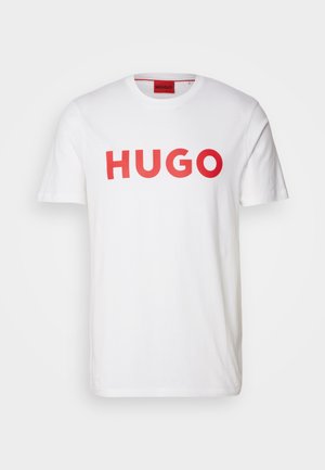 Bijela pamučna majica s odvažnim crvenim natpisom "HUGO" na prednjoj strani, okruglim izrezom i kratkim rukavima. Glatka tekstura, klasičan kroj.