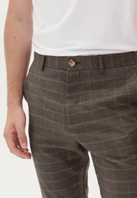 Graue Karohosen mit einer glatten Textur, die über einen Knopfverschluss und seitliche Taschen verfügen. Das Design umfasst subtile horizontale Linien.