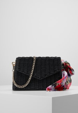 Borsa a tracolla nera intrecciata con catena e un tocco di sciarpa di seta a motivo floreale. Presenta una chiusura a patta e una superficie texturizzata.