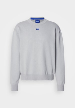 Světle šedý svetr s kulatým výstřihem a ribbovanými manžetami. Na hrudi se nachází modré logo a kontrastní modrý vnitřní límec.