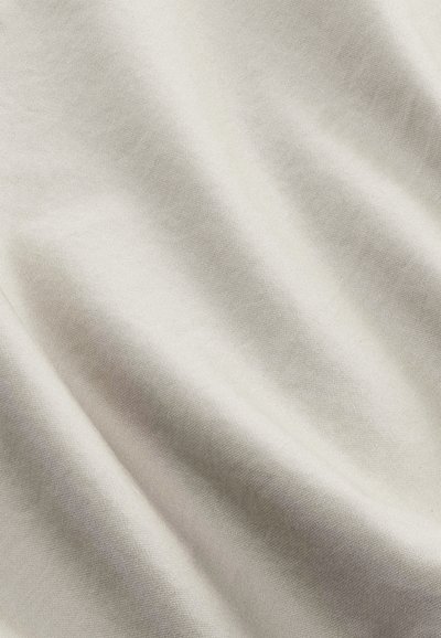 Tissu beige clair, doux et lisse, avec des plis subtils créant des ombres douces et une texture délicate.