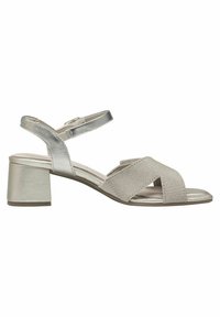 Sandales ouvertes couleur beige clair avec un design croisé, un talon métallique et une sangle de cheville réglable, le tout avec une texture lisse.