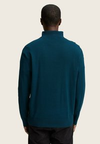 Dunkelblaue Pullover mit hohem Kragen, gerippten Bündchen und Saum, aus einem glatten Strickstoff, von hinten betrachtet.