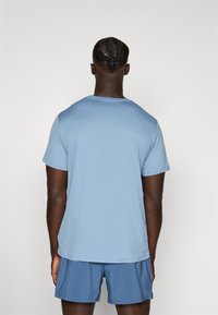 T-shirt bleu clair à manches courtes avec une texture lisse et un col rond, associé à un short bleu. Design simple, sans motifs ni accents visibles.