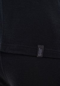 Black fitted clothing with a smooth texture, featuring a subtle JBS label on the seam. The material appears lightweight and stretchy.