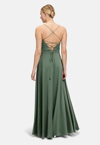 Long, green dress made of smooth fabric. Features a crisscross back design with adjustable ties and a flowing silhouette.