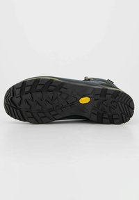 Suola di scarpa in gomma nera con patttern aggressivo, bordi rinforzati e logo Vibram giallo. Superficie liscia con scanalature di trazione ben definite.